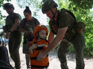 A police officer puts body armour on Milana, 4, during her evacuation from her house